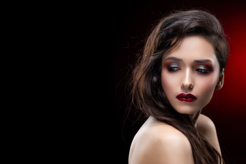 Portrait of a beautiful glamorous brunette girl with naked shoulders. Shimmering makeup, red lips.