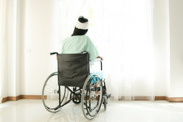 Young woman in hospital wheel chair. Looking at window. Beautiful chinese woman. Medical, health insurance concept.