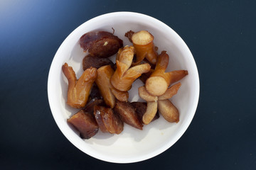 Hot dog, fried sausage, fried in a bowl placed on wood, like the night sky.