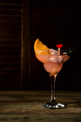 Ice cold Margarita Cocktails in stem glasses on dark wooden backgorund, copy space