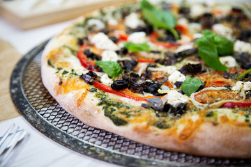 Freshly baked italian vegetarian pizza on a metal mesh pan