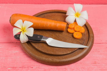 carrot sliced with knife on wood chopping Board  on pink wood
