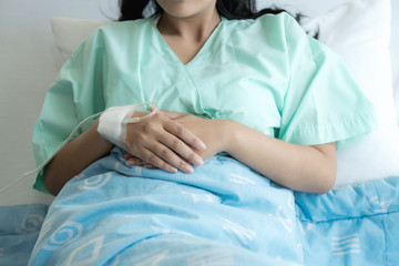 Fototapeta premium Young patient alone in bed. Sleeping in hospital bed. Body shot. Young beautiful chinese woman.