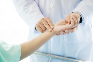Doctor with patient. Routine health check and holding hands. Male medical doctor with young chinese woman.