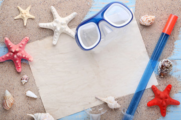 Blank sheet of paper with seashells on beach sand