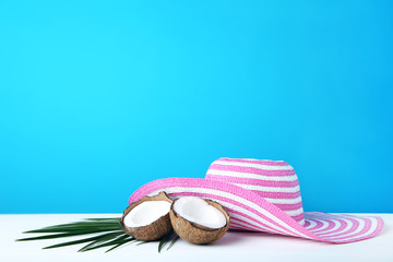 Coconuts with palm leaf and hat on blue background