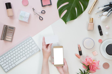 Flat lay, top view of pastel woman office table desk. Workspace with paintbrush, laptop, peony flowers, palm tropical leaves, cosmetics, diary on white and pink background. Online shopping concept