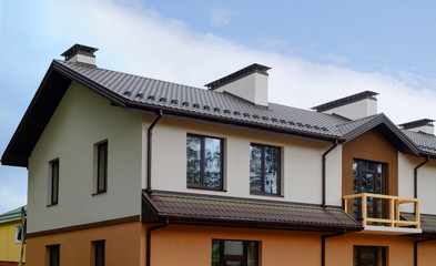 New cottage house with metal roof, rain gutter and balcony. Chimney and ventilation system