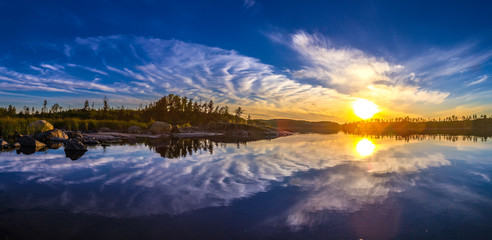 Sunset in the reflection of water. The nature of Finland. Camping. Unusual clouds. Reflection of clouds in the water.