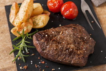 cooked beef steak with fried potatoes and tomatoes
