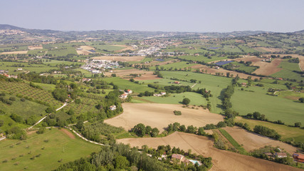 Aerial view of the countryside between Tuscany and Marche in Italy during a beautiful sunny day in summer. The fields are cultivated and the hills are rich in trees and forests.