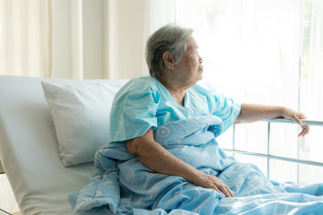 Elderly patient alone in bed. Alone and stress, missing her grand children. Looking at window. Very senior, old chinese woman.