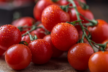 Small red cherry tomatoes on rustic background. Cherry tomatoes on the vine