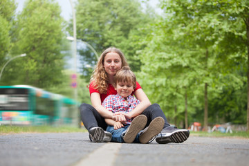 Girl and her little brother sitting on a path
