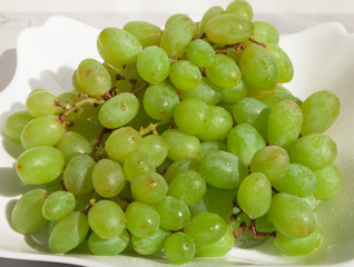 Green grapes in a white plate on the table