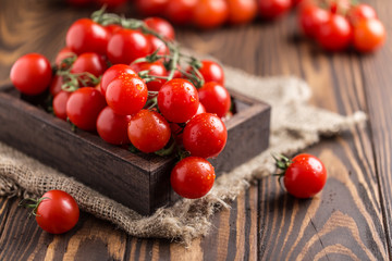 Small red cherry tomatoes on rustic background. Cherry tomatoes on the vine - Powered by Adobe