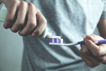 Man putting toothpaste on toothbrush. Dental care concept