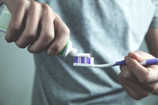 Man Putting Toothpaste On Toothbrush. Dental Care Concept