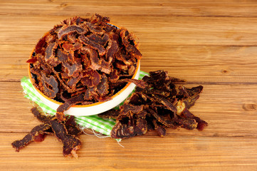 Bowl of shredded biltong meat on a wooden background © philip kinsey