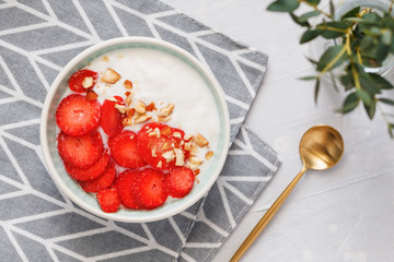 Top view of bowl with coconut yoghurt, fresh strawberries and almonds. The concept of breakfast and a healthy lifestyle. Scandinavian style.