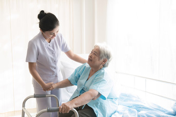 Nurse with patient. Routine health check and assisting elderly patient to walk. Female nurse with senior chinese woman.