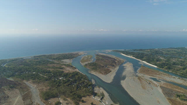 Aerial view of rver flowing into the sea in Philippines,Luzon. ropical landscape with sandy coast and river among farmer fields flowing into the blue ocean