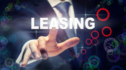 A hand selecting a Leasing business concept on a clear screen with a colorful blurred background.