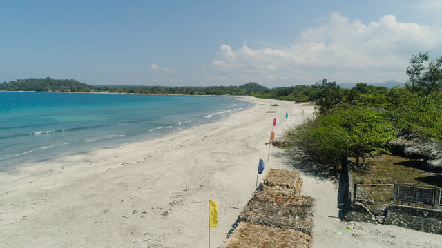 Beautiful tropical beach Cabugao with white sand and palm trees in the Philippines, Luzon. Aerial view of coast with beach and turquoise water.