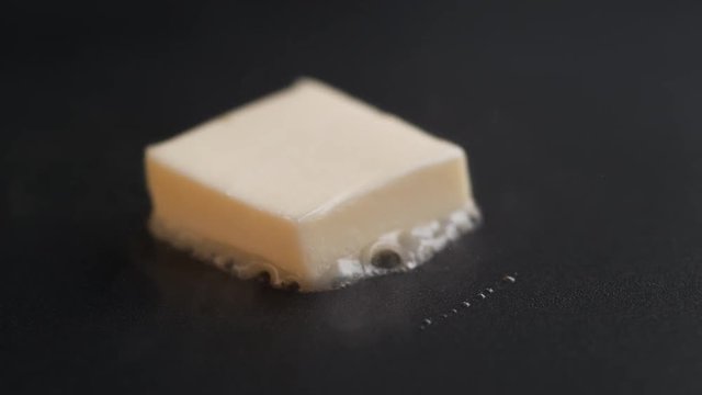 Butter melting on heated non stick pan. Shot with high speed camera, phantom flex 4K. Slow Motion.