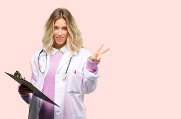 Young doctor woman, medical professional looking at camera showing tong and making victory sign with fingers