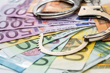 Steel handcuffs on euro note background, close up