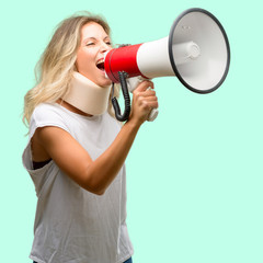 Young injured woman wearing neck brace communicates shouting loud holding a megaphone, expressing success and positive concept, idea for marketing or sales