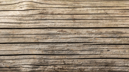 Fototapeta premium the texture of old dry weathered cracked wood, cracks along the fibers of logs, close-up abstract background
