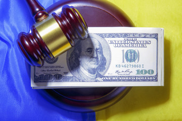 Dollar banknotes and judge's gavel on the background of yellow and blue colors as symbol of corruption in the judicial system in Ukraine