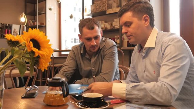 Two Business Men planning work with Pen and Paper on a Lunch in Cafe
