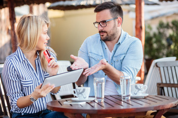 Young couple arguing over online shopping. Woman holding credit card and a tablet