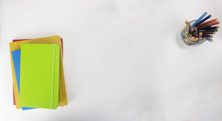 An artistic desk on an isolated white background with colored pencils and notebooks 
