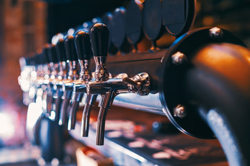 Beer tap array in beer bar - obrazy, fototapety, plakaty