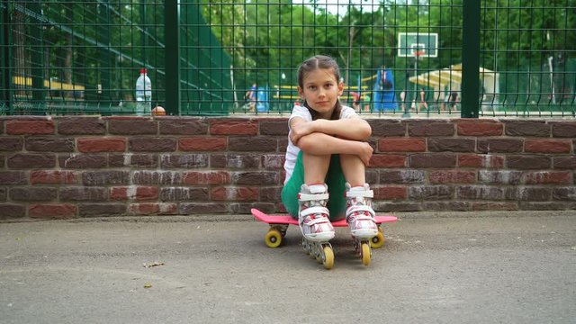 beautiful young girl in park. lonely bored and tired teen relaxing after roller skating outdoor.