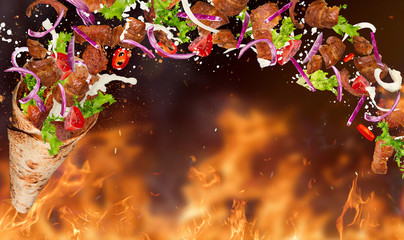 Turkish Kebab yufka with flying ingredients and flames.