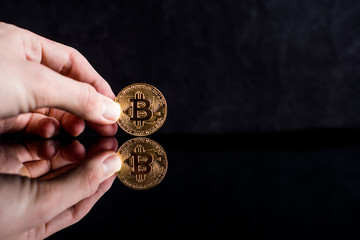 Fototapeta premium bitcoin in hand on a black background. Mirror reflection of a coin