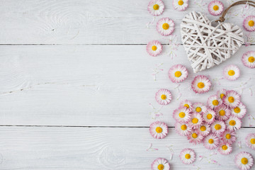 Daisies, petals and hearts on a wooden light background