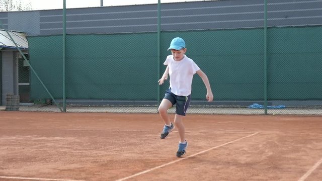 Kid Boy does exercises before playing Tennis on a Cort