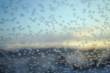 snowflakes and frost pattern on frozen windowpane.
