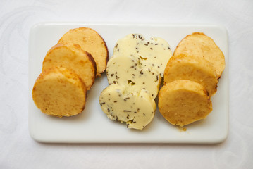 Butter flavored with herbs and spices on ceramic cutting board, close-up. 