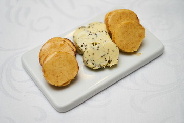Butter flavored with herbs and spices on ceramic cutting board, close-up. 