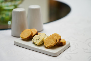 Butter flavored with herbs and spices on ceramic cutting board, close-up. 