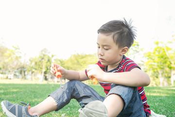 Young boy blowing bubble in park. Chinese boy enjoying playing with his bubble mixture in park.