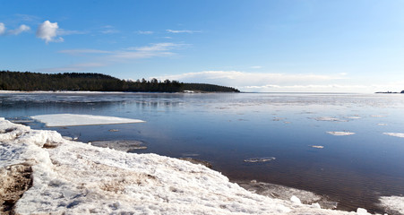 Reflection of blue sky and clouds in the freezing thin ice of Lake Ladoga in Karelia