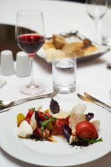 Vegetarian food with marinated tomatoes, arugula, mozzarella cheese, balsamic jelly, olive oil. Delicious healthy food concept, close-up